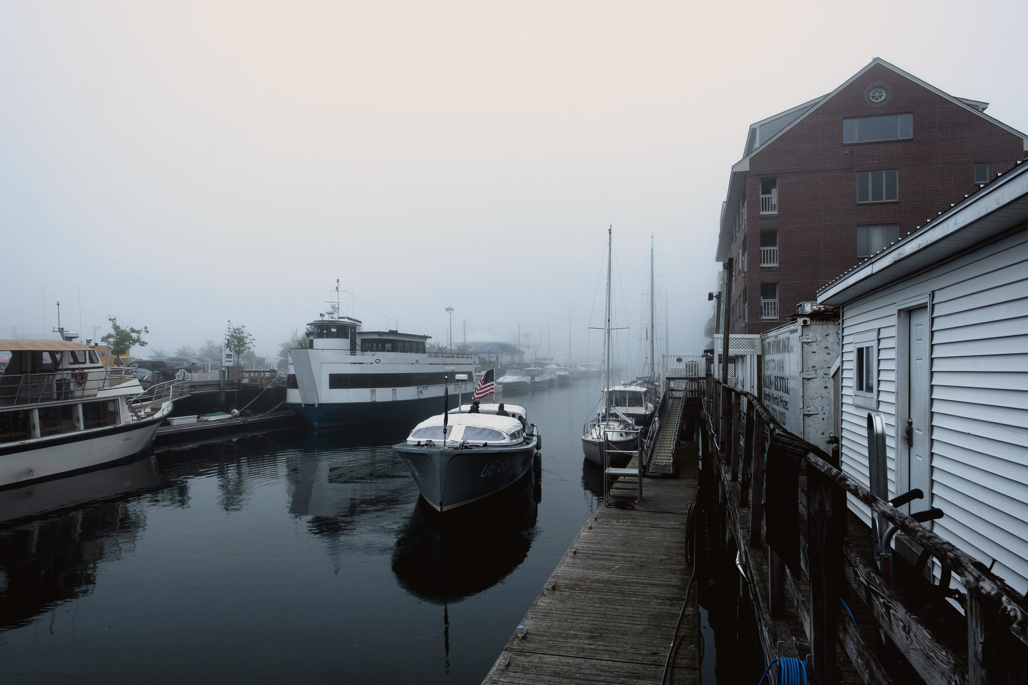 Fog on Custom House Wharf at dawn, boats moored along the working waterfront in Portland, Maine